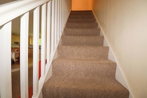 Eine Teppichstufen Treppe mit weißen Geländern, die zu einer oberen Etage führt.