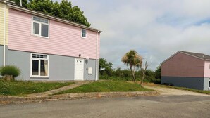 A two-story building with a pink and grey exterior, a white door, and a small window. - 20 Atlantic Reach (St. Columb Major)