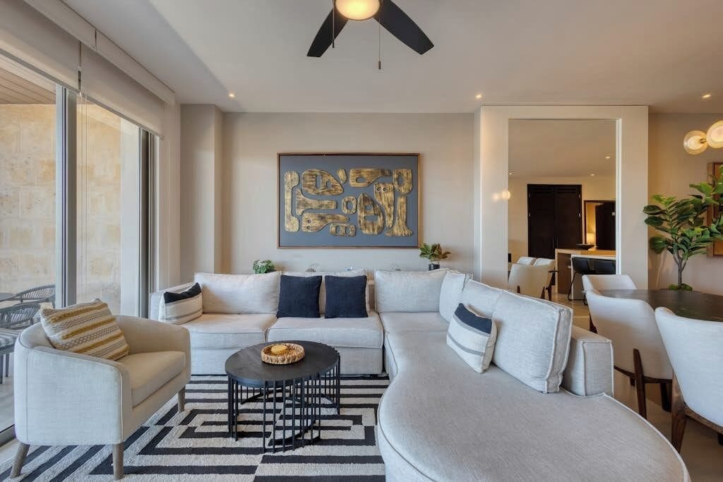 Uma sala de estar moderna com um sofá seccional, uma mesa de centro e um espaço de jantar com cadeiras.