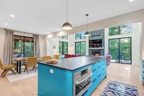 A modern kitchen with a blue island, large windows, and a fireplace. - Luxury Log Cabin w Hot Tub & Sauna near Trail (McGaheysville)