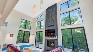 A spacious living room with large windows, a fireplace, and a red leather couch.