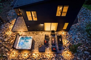 Una casa moderna con vasca idromassaggio, area salotto esterna e patio in pietra.