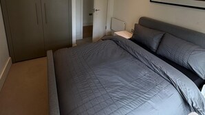 Een slaapkamer met een bed, een kledingkast en een schilderij aan de muur.