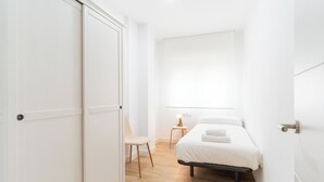 A bedroom with a bed, a chair, a nightstand, and a window. - Apartment on the beach - Paseo marítimo de Almería (Almería)