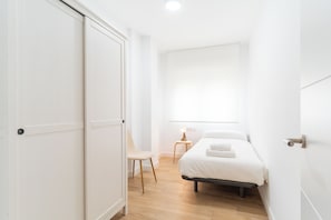 A bedroom with a bed, a chair, a nightstand, and a window. - Apartment on the beach - Paseo marítimo de Almería (Almería)