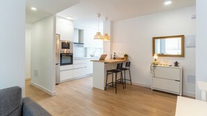 A modern kitchen with white cabinets, a central island, and pendant lighting. - Apartment on the beach - Paseo marítimo de Almería (Almería)