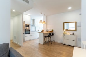 A modern kitchen with white cabinets, a central island, and pendant lighting. - Apartment on the beach - Paseo marítimo de Almería (Almería)