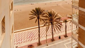 A high-rise building with a view of a beach and palm trees. - Apartment on the beach - Paseo marítimo de Almería (Almería)