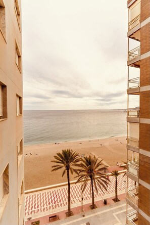 A high-rise building with a view of a beach and palm trees. - Apartment on the beach - Paseo marítimo de Almería (Almería)