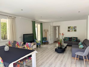 Ein modernes Wohnzimmer mit einem Flachbildfernseher, einer Couch, einem Esstisch und einem Stuhl.
