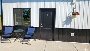 A building with a black door, a window, and a small table with two chairs. - Cozy 7-Room Boutique Motel (Estelline)