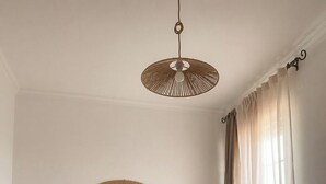 Una camera da letto con un letto in legno, una testiera intrecciata, un lampadario e tende leggere.
