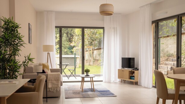 Una sala de estar moderna con sofá, mesa de centro, televisor y comedor.