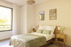 A bedroom with a bed, bedside tables, a window, and two wall-mounted artworks. - Zenao Appart'hôtels Aix Carnot (Aix-en-Provence)