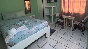 A bedroom with a bed, a desk, a chair, a television, and a wardrobe. - The Victor's Inn  (Gros Islet)