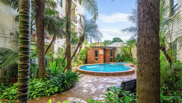 A pool surrounded by lush greenery and a building with a tiled patio. - Glebe Corner Walkable City Fringe Base with Pool (Glebe)