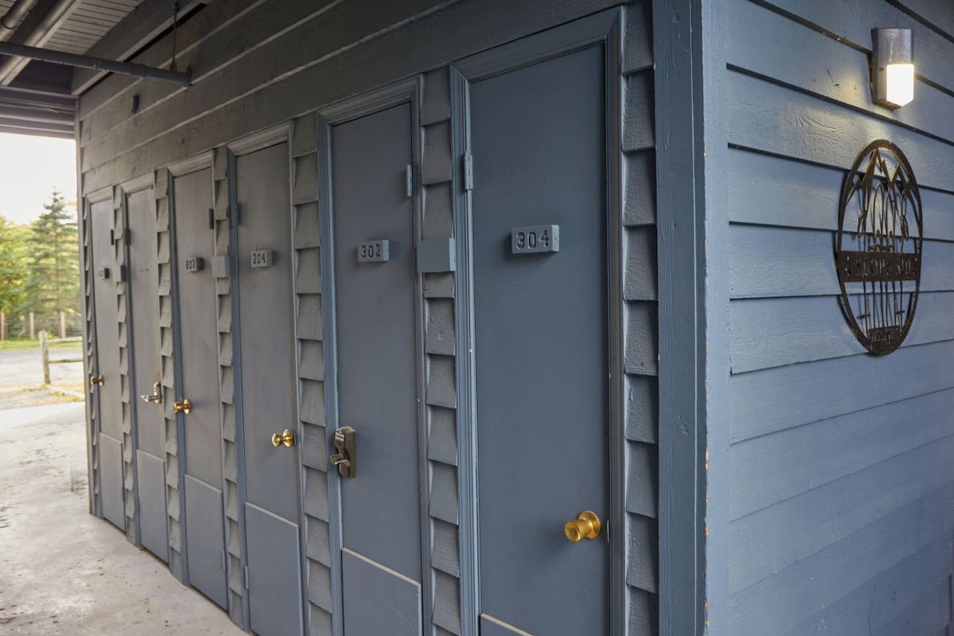 A row of grey metal lockers with numbers 302, 304, and 204 visible, and a metal plaque on the wall.
