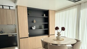 Eine moderne Küche mit Holzausbau, einer eingebauten schwarzen Regaleinrichtung und einem Essbereich mit rundem Tisch und Stühlen.
