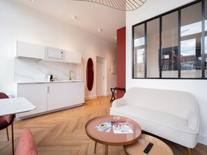 Ein modernes Wohnzimmer mit Sofa, Couchtisch, Esstisch und Küchenzeile.