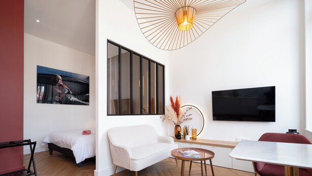 Una sala de estar moderna con un sofá, una mesa de comedor, un televisor y una lámpara de techo original.