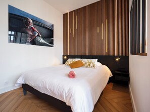 Un dormitorio moderno con una cama, un televisor montado en la pared y un panel de pared de madera.