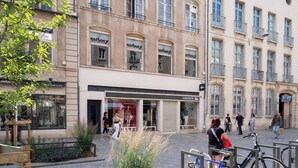 A building with multiple storefronts, including a visible Lacoste store. - Les perchoirs de Stanislas 2 - logement de standing hyper centre (Nancy)