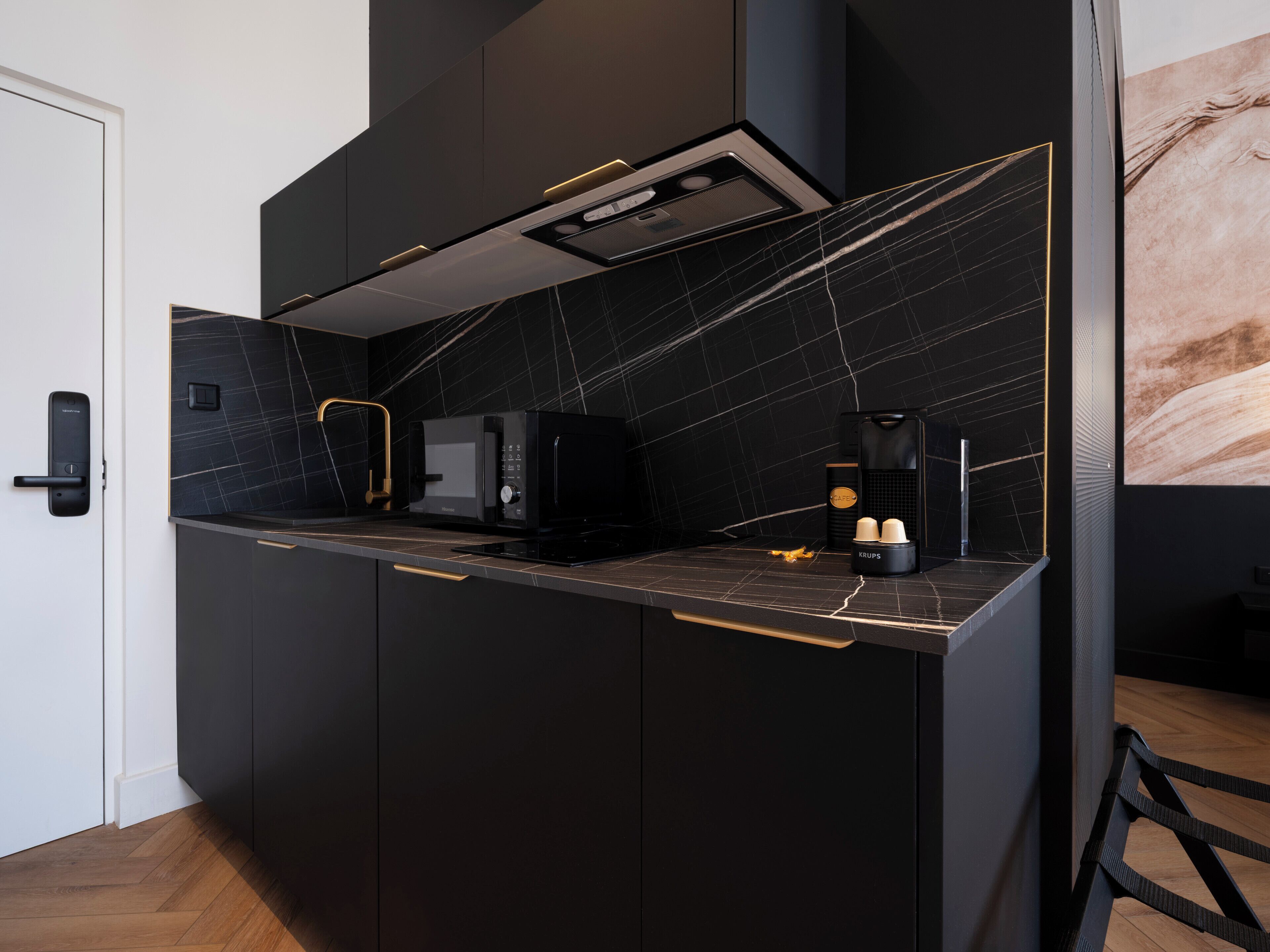 Eine moderne Küche mit schwarzem Arbeitsplatz, einer eingebauten Mikrowelle, einer Kaffeemaschine und einer Krups-Kaffeemaschine.