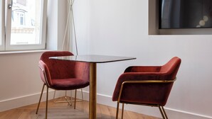 A modern room with a round table, two red chairs, a floor lamp, and a TV mounted on the wall. - Les perchoirs de Stanislas 2 - logement de standing hyper centre (Nancy)