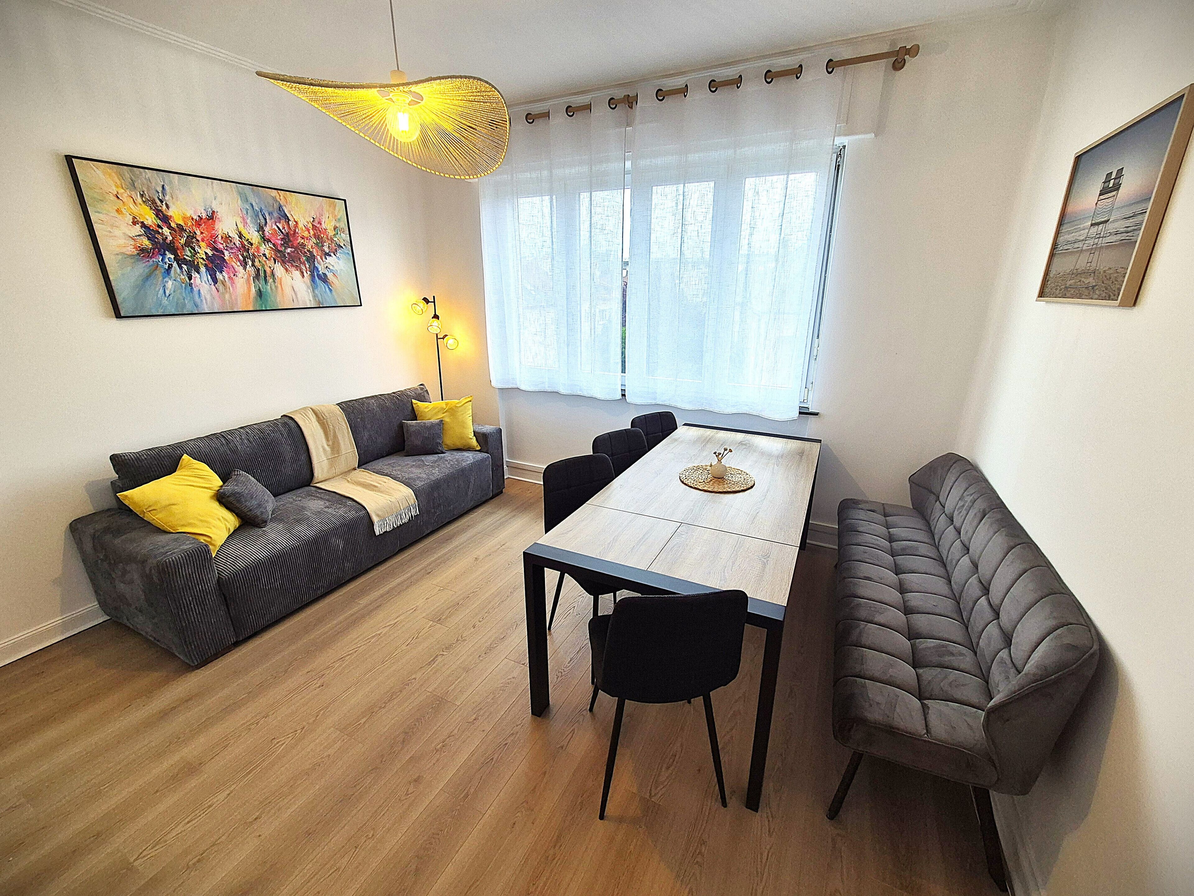 Ein modernes Wohnzimmer mit Sofa, Esstisch, Stühlen und Kunstwerken.