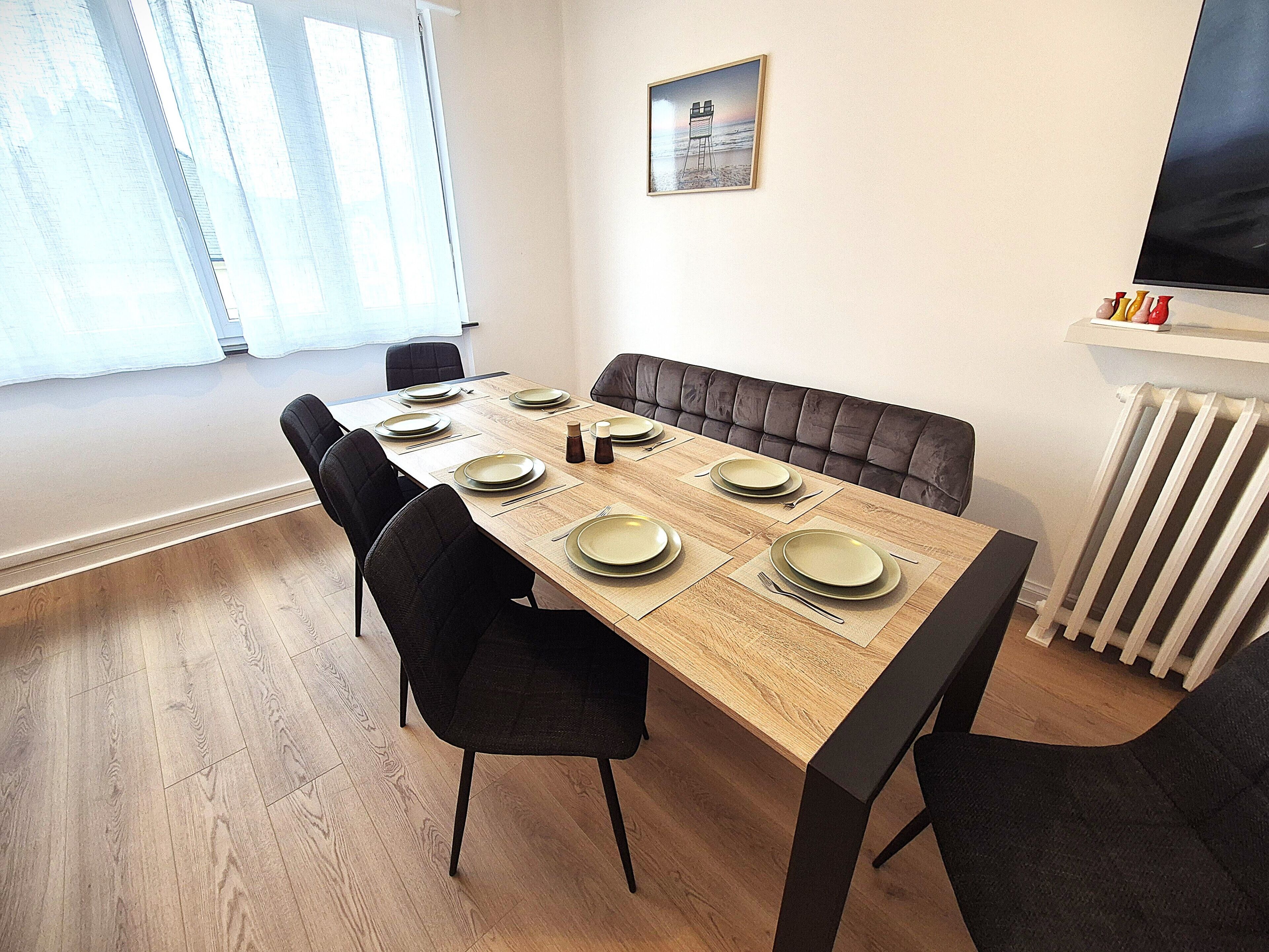Een eetgedeelte met een lange tafel, zwarte stoelen en een comfortabele bank.