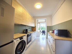 Une cuisine de taille réduite équipée d’un lave-linge, d’un four à micro-ondes et d’un évier.