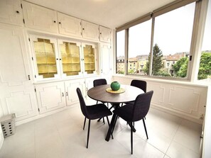 Un coin repas avec une table ronde, des chaises noires et un vase vert.