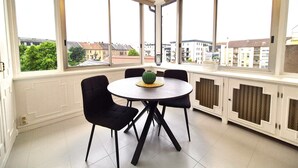 A room with a round table, four chairs, large windows, and a radiator. - Rock in Share - Strozzi Suites - Brand-New Luxury 4-Bedroom Apartment with (Thionville)