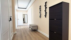 A hallway with wooden flooring, a black cabinet, and a bench. - Rock in Share - Strozzi Suites - Brand-New Luxury 4-Bedroom Apartment with (Thionville)