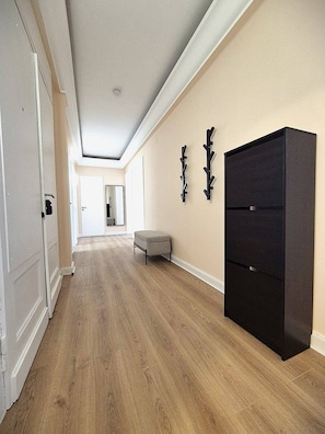 Un couloir doté d’un plancher en bois, d’une armoire noire et d’un banc.
