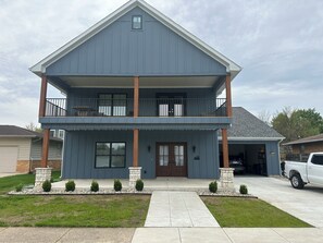Ein zweistöckiges Haus mit Veranda, Garage und Auffahrt.