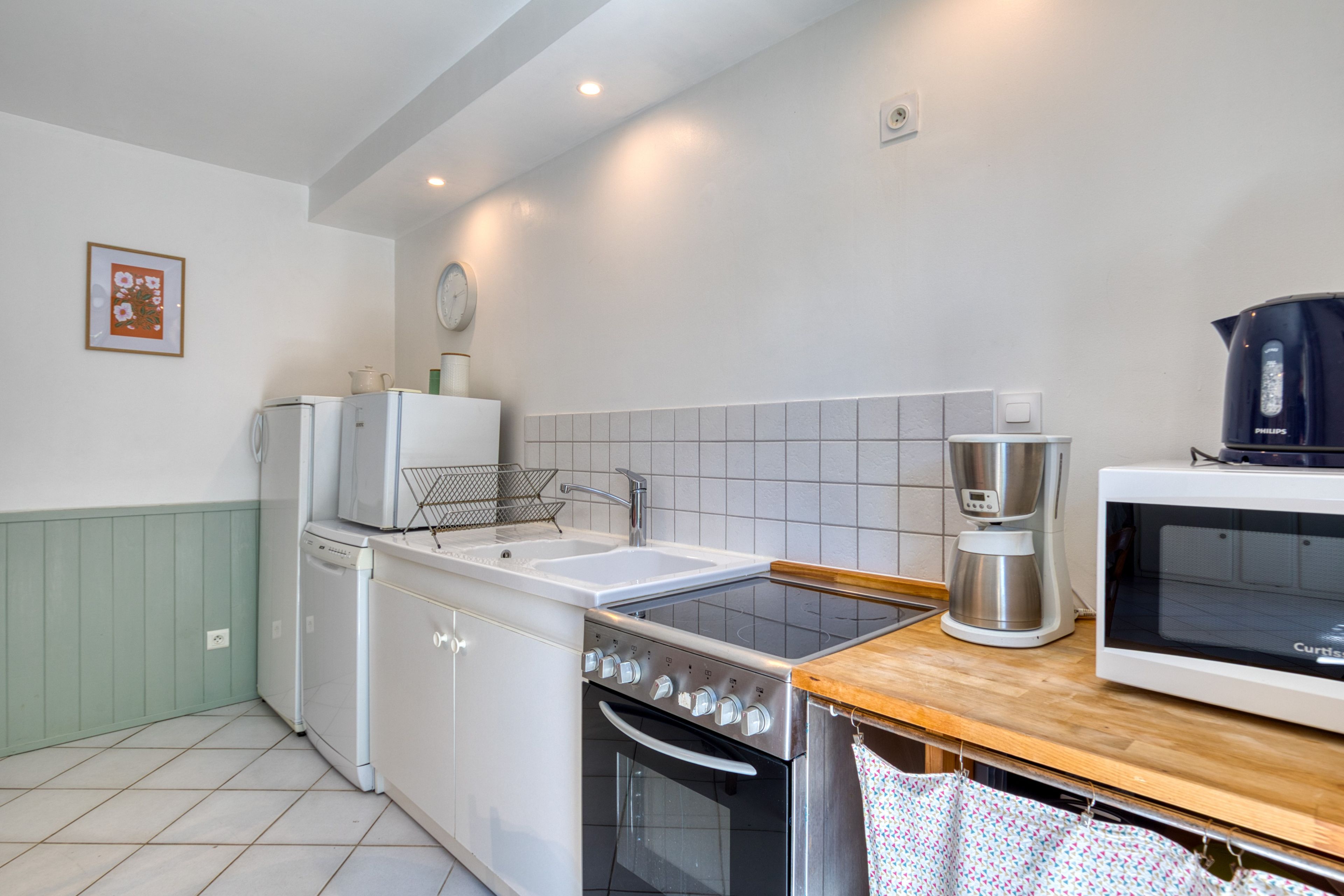 Una cucina compatta con elettrodomestici bianchi, un piano di lavoro in legno e uno schienale piastrellato.