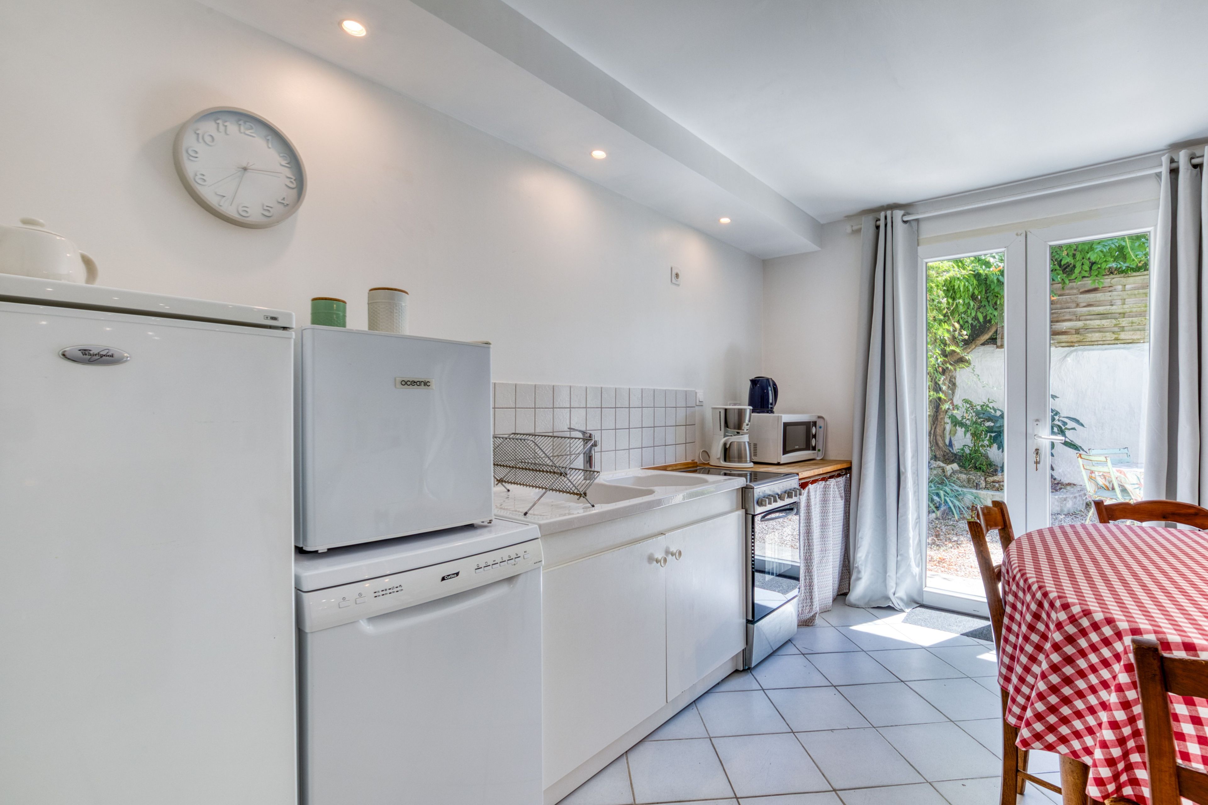 Une cuisine compacte équipée d’un lave-vaisselle, d’un four à micro-ondes et d’une cuisinière. Un coin repas avec une table et des chaises est également disponible.