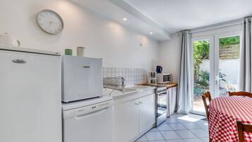 Une cuisine compacte équipée d’un lave-vaisselle, d’un four à micro-ondes et d’une cuisinière. Un coin repas avec une table et des chaises est également disponible.