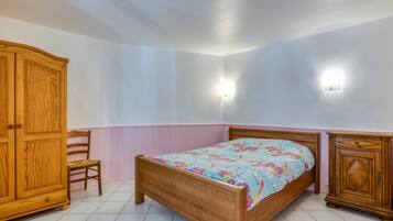 Een slaapkamer met een houten bed, een houten kledingkast, een stoel en twee wandlampen.
