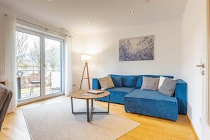 Un salon avec un canapé bleu, une table basse ronde et une lampe.