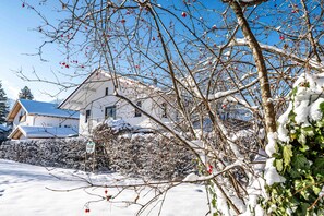 Ein schneebedecktes Wohngebiet mit einem Haus, einem Hecken und einem Schild.