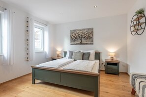 Ein Schlafzimmer mit einem Bett, zwei Nachttischen, einer Wandablage und einem Fenster mit Vorhängen.