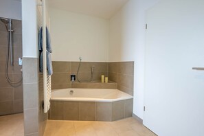 Ein modernes Badezimmer mit freistehender Badewanne, einer Duschbrause und einem Handtuchhalter.