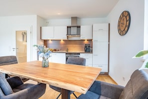 Une cuisine moderne avec des meubles blancs, un plan de travail en bois et une horloge au mur.