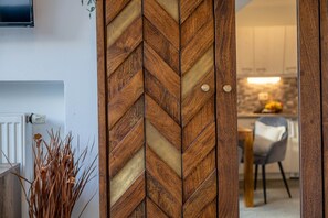 A wooden door with a chevron pattern, a white radiator, and a plant with dried leaves. - Apartment Unternberg (Ruhpolding)