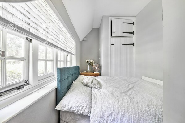 A bedroom with a bed, a nightstand, a window with blinds, and a wardrobe. - Villa Sleeps up to 17 - Hot Tub, Garden, Parking (Pinner)