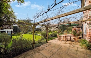Une terrasse de jardin agrĂ©mentĂ©e dâune pergola, dâune table avec des chaises et dâun mur en briques.