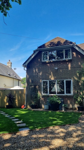 A two-story house with a brick exterior, large windows, and a well-maintained lawn.