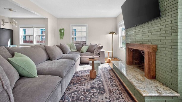 A modern living room with a sectional sofa, a fireplace, and a large window. - 6 beds / close to SCSU, DT, & Lake George (St. Cloud)